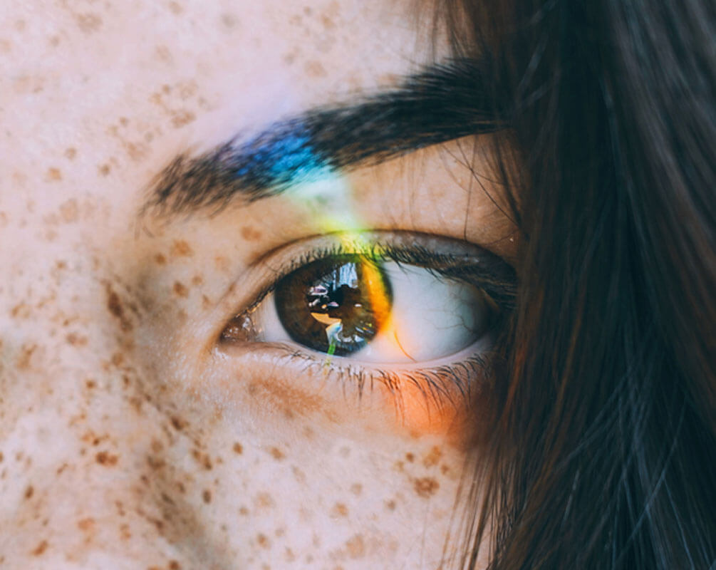 Freckled women hazel eye, light glared retina showing clutter from clean, colour from bland, & ego from pride phases of branding